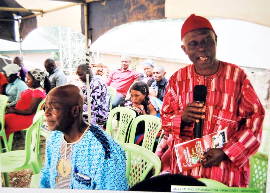 An older man speaking to people under a tent
