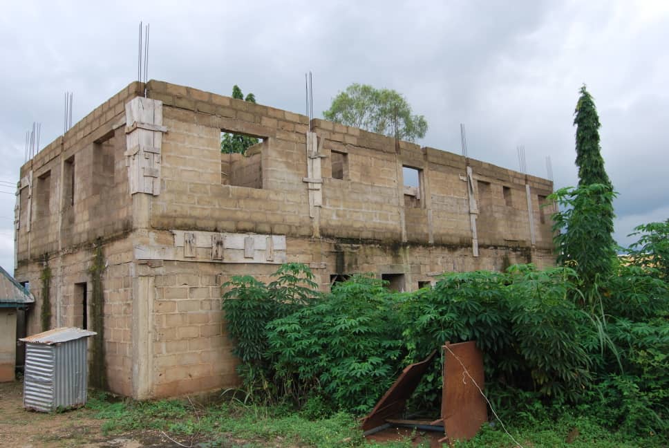 An unfinished concrete building surrounded by vegetation